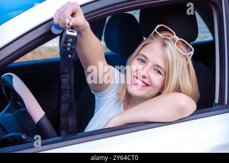 Eine junge Frau, die Autoschlüssel in einem Auto hält Stockfoto