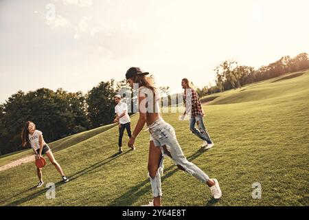 Sommeraktivität. Gruppe junger Leute in Freizeitkleidung, die Frisbee spielen, während sie unbeschwert im Freien verbringen Stockfoto