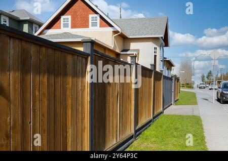 Großer neuer Holzzaun um das Haus und die Bäume. Harter Holzzaun mit grünen Bäumen und Weg. Zäune und Tore. Hochwertiger Zaun. Straßenfoto. Stockfoto