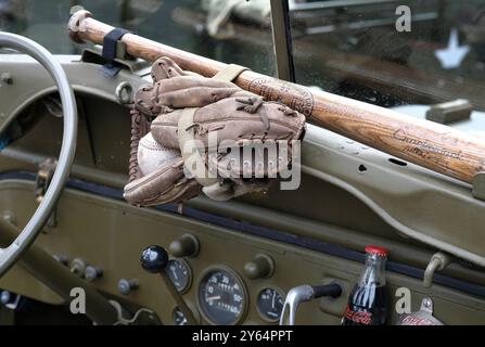 Baseballschläger, Handschuhe und Ball auf dem Armaturenbrett eines alten Militärjeeps Stockfoto