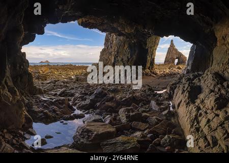 Panoramablick auf den natürlichen Bogen am Playa de Campiecho (nur bei Ebbe zu besichtigen), von einer Höhle aus gesehen. Die zerklüftete Küste von Playa de Campiechos i. Stockfoto