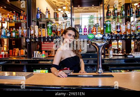 Ava Nicholson, ein schönes weibliches Model, posiert für ein Foto hinter der Bar im Dundee Queens Hotel in Schottland Stockfoto