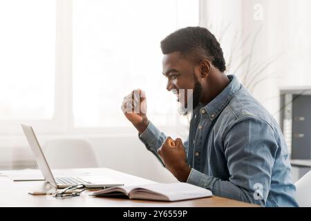 Afrikanische amerikanische Geschäftsmann feiert Sieg bei der Arbeit Stockfoto