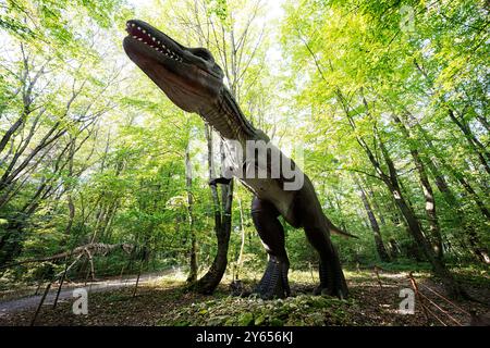 Realistische Dinosaurier-Skulptur in üppiger Waldlandschaft Stockfoto