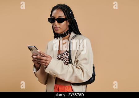 Eine stilvolle junge Frau greift selbstbewusst auf ihr Handy ein. Stockfoto