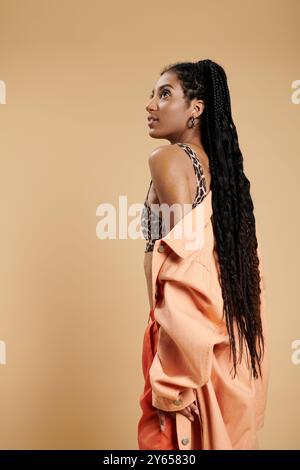 Eine wunderschöne junge Frau mit langen Haaren zeigt ihren einzigartigen Sinn für Mode in einer lebendigen Umgebung. Stockfoto