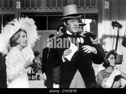 Dieser typische Engländer unter den Schauspielern, Rex Harrison, wird auf ihn aufpassen müssen. Er läuft Gefahr, als Escort zu einer attraktiven Frau bei Ascot (dem jährlichen, modebewussten Rennen-Treffen) typisiert zu werden. Hier macht er in zwei aufeinanderfolgenden Filmen das Gleiche , hier mit Jeanne Moreau in The Yellow Rolls Royce aber auch mit Audrey Hepburn in My Fair Lady . 20. Juni 1964 Stockfoto