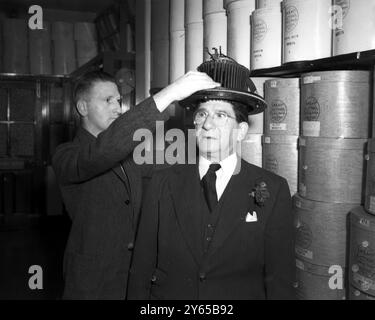 London : brauchst du einen Hut? Unabhängig von der Größe oder Form seines Kopfes werden die Sorgen eines Mannes verschwinden , wenn er in eine St James ' s Street Hatters tritt , eine der malerischsten Lokale Londons . Für einige Momente stellt sich der Kunde in der Rolle eines Beefeaters vor , während er für einen neuen Hut mit einem " Konformator " ( Maßmesser ) gerüstet ist . Auf der Maschine befindet sich eine Reduziervorrichtung , die einen Papierausschnitt aus dem Kopf erzeugt , der in die Akten des Unternehmens für zukünftige Zwecke eingeht . All das wird von den St. James's Street Hatters, Lock and Co. 1952 gemacht Stockfoto