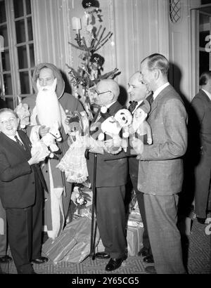 Tommy Trinder, gekleidet als Father Christmas, erhält Spielzeuge von Sir Louis Sterling (Brillen) Wee Georgie Wood und Albert Whelan (rechts). Sie brachten Spielzeug zum Aufhängen an den fünf Weihnachtsbäumen bei einem Mittagessen im Savoy Hotel, das vom Water Rats and Variety Club of Great Britain gehalten wurde. Das Spielzeug wird anschließend unter Kinderheimen und Krankenhäusern verteilt. 16. Dezember 1954 Stockfoto