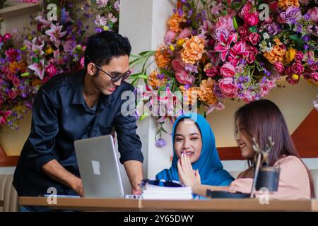 Eine Gruppe fröhlicher asiatischer Freelancer löst erfolgreich Fallprobleme und Prüfungen, während sie an Unternehmensaufgaben in einem Café im Café arbeitet. Für Gruppe Stockfoto