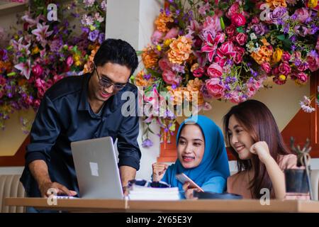 Eine Gruppe fröhlicher Schüler präsentierte ihr Handy vor dem Laptop des Lehrers im Café. Für Gruppe, Unternehmen, Bildung, Stockfoto
