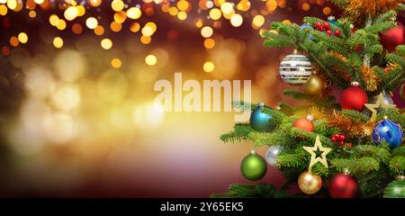 Festliche elegante Weihnachtsszene mit der Nahaufnahme eines Tannenbaums mit Ornamenten und beleuchtetem Fantasy-Hintergrund mit vielen verschwommenen, glänzenden, warmen Lichtern Stockfoto