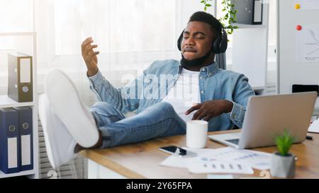 Freundliche Mitarbeiter virtuelle Gitarre spielen und Musik hören am Arbeitsplatz Stockfoto