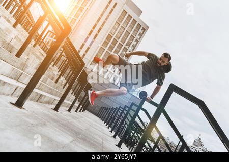 Sich selbst herausfordern. Voller Länge eines hübschen jungen Mannes in Sportkleidung, der beim Training draußen über das Geländer springt Stockfoto