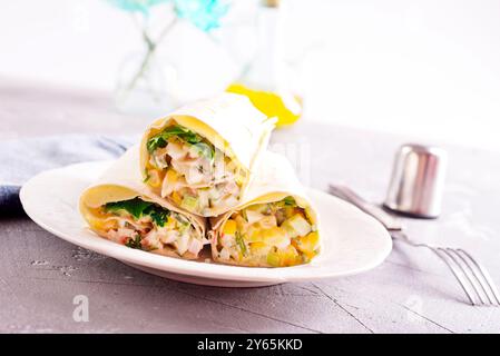 Füllung, Gurke und Mais werden dem entfalteten Pitabrot hinzugefügt. Herstellung von Pita-Brötchen. Stockfoto