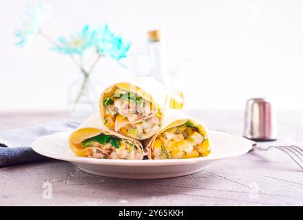 Füllung, Gurke und Mais werden dem entfalteten Pitabrot hinzugefügt. Herstellung von Pita-Brötchen. Stockfoto