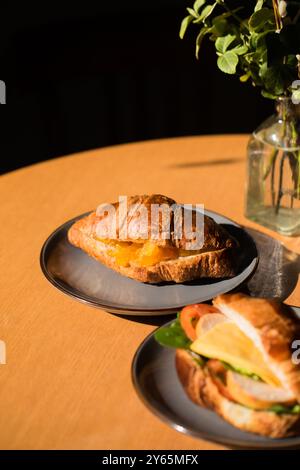 Zwei Croissants auf Tellern, eines mit Schinken und Käse, das andere mit Orangenmarmelade Stockfoto