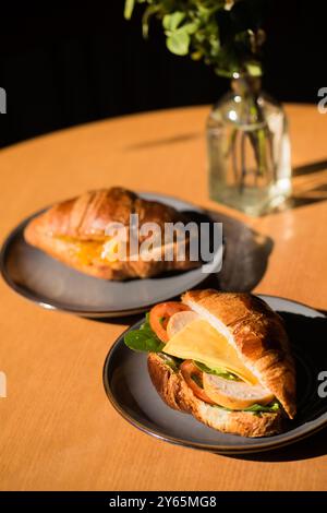 Zwei Croissants auf Tellern, eines mit Schinken und Käse, das andere mit Orangenmarmelade Stockfoto