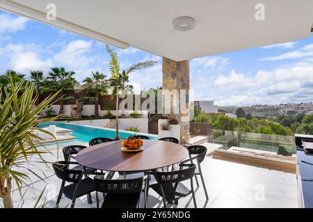 Ein atemberaubender Blick von der Terrasse einer Luxusvilla mit Blick auf eine üppige Landschaft und einen privaten Pool, mit stilvollem Restaurant im Freien Stockfoto