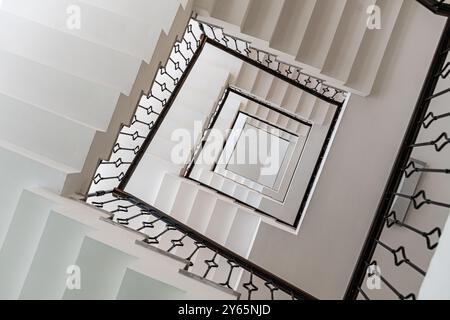 Eine faszinierende vertikale Aufnahme einer weißen Wendeltreppe, die geometrische Eleganz und klare Linien unterstreicht Stockfoto