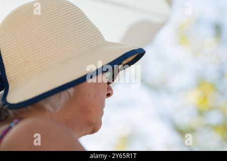 Seitenansicht einer nicht erkennbaren Großmutter mit breiter Krempe, die wegblickt, in einer ruhigen Umgebung im Freien. Stockfoto