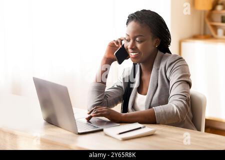 Besetzt Schwarz Geschäftsfrau Arbeiten im Büro mit Smartphone und Laptop. Stockfoto