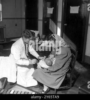 Mit der Einführung des Nationalen Gesundheitsdienstes im Juli 1948 kann diese junge Mutter nun kostenlos für ihr Baby gesundheitlich versorgt werden . Dies hat vielen jungen Familien in der Gegend von Bootle in der Nähe von Liverpool geholfen, deren Leben von Armut und Armut heimgesucht wird. September 1948 Stockfoto