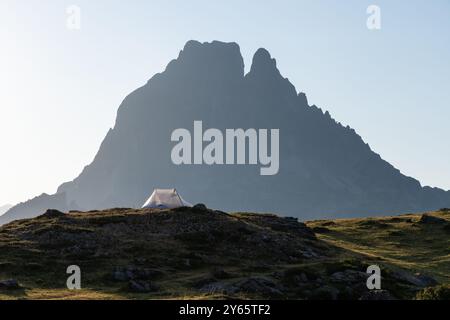 Ein einzelnes Zelt vor der majestätischen Kulisse des Pico Midi d'Ossau in der Gegend von Lacs d'Ayous in den französischen Pyrenäen, das die ruhige und zerklüftete Atmosphäre zeigt Stockfoto