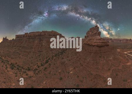 Ein majestätischer Panoramablick auf die Milchstraße, die sich über die zerklüfteten, geschichteten Klippen des Valley of the Gods in Utah unter einem sternenbesetzten Himmel erhebt Stockfoto