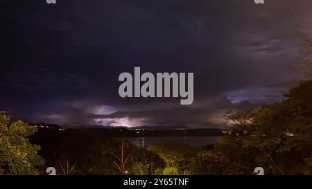 Der dramatische Nachthimmel beleuchtet die Wolken über dem ruhigen Golf von Papagayo in Costa Rica, mit üppiger tropischer Vegetation im Vorfeld Stockfoto