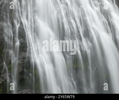 Eine Nahaufnahme, die den sanften Fluss eines Narada-Wasserfalls erfasst und die seidenweiche Textur von kaskadierendem Wasser über moosigen Felsen zeigt Stockfoto