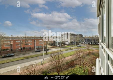 Ein ruhiger Blick auf ein Wohnviertel, von einer Wohnung aus gesehen, mit Gebäuden, Fahrzeugen und Straßen unter einem blauen Himmel mit Wolken. Stockfoto