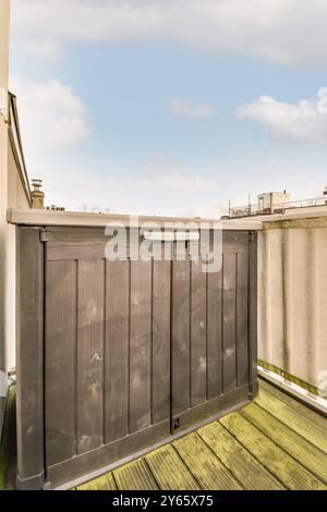 Ein kompakter, moderner Stauraum auf einem städtischen Balkon mit Holzfußboden und klarem blauem Himmel. Stockfoto