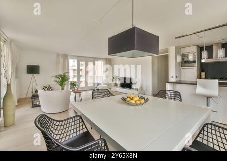 Helle und geräumige kombinierte Küche und Wohnbereich mit modernen Möbeln und großen Fenstern. Stockfoto