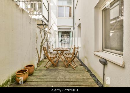 Ein einladender Terrassenbereich mit Holzmöbeln und Tontöpfen, eingebettet zwischen Stadtmauern. Stockfoto