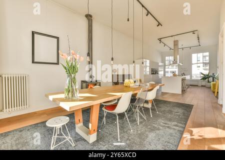 Ein gut beleuchteter, moderner Speisesaal mit Holztisch, Designer-Stühlen und einem gemütlichen Kamin für ein warmes Ambiente. Stockfoto