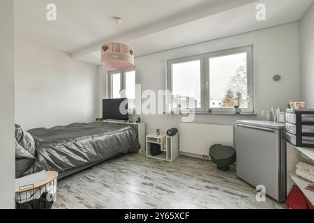 Modernes Schlafzimmer mit Doppelbett, minimalistischer Einrichtung und viel Tageslicht durch zwei Fenster. Stockfoto