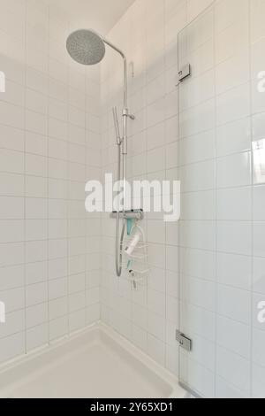 Ein sauberes, modernes Badezimmer mit Dusche, großem Regenduschkopf und weißen Fliesen mit minimalistischen Armaturen und einem Caddy für das wesentliche. Stockfoto