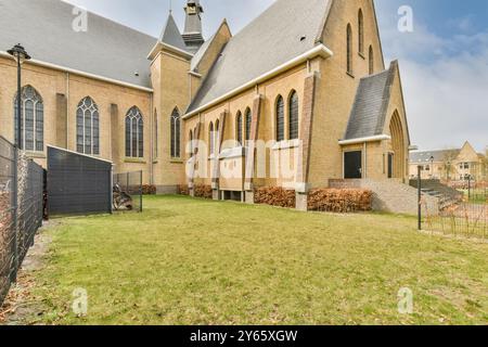 Ein Blick auf eine große Kirche mit gotisch inspirierter Architektur, bogenförmigen Fenstern und steilem Dach vor einem bewölkten Himmel. Stockfoto