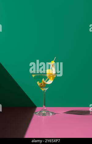 Ein klassischer Dry Martini Cocktail, elegant in einem Martini-Glas präsentiert, garniert mit einer grünen Oliven- und spritzigen Zitronenmischung im Kontrast zu einem Grün Stockfoto