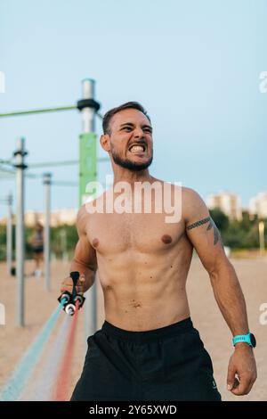 Ein fokussierter Mann macht ein intensives Calisthenics-Workout in einem Outdoor-Fitness-Park und zeigt seine körperliche Kraft und Entschlossenheit Stockfoto