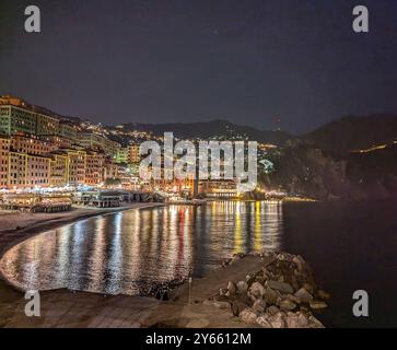 Ein wunderschönes Nachtfoto von Camogli, Italien, das die beleuchtete Küstenstadt entlang der ruhigen Mittelmeerküste zeigt. Stockfoto