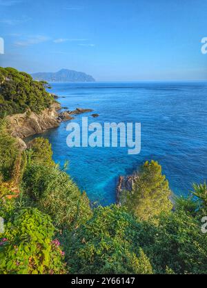 Ein atemberaubender Blick auf die zerklüftete italienische Küste entlang der Riviera, wo das Meer auf dramatische Klippen und üppiges Grün trifft. Stockfoto