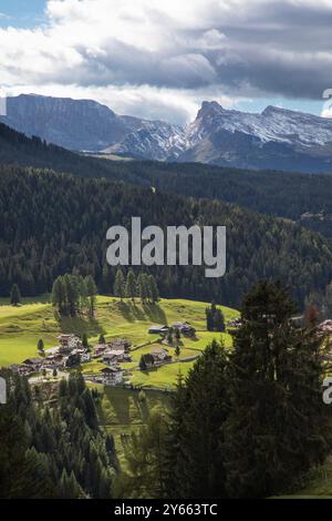 Die dramatischen Gipfel der Dolomiten überragen das bezaubernde Alpendorf Corvara in Norditalien und schaffen einen atemberaubenden Kontrast. Stockfoto