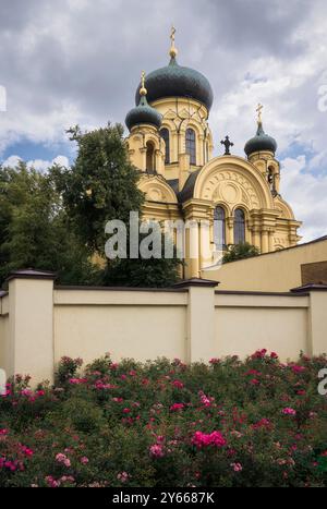 Ein atemberaubender Blick auf Warschaus Metropolitan Cathedral St. Maria Magdalena, umgeben von blühenden Rosen und dramatischem Himmel, Polen Stockfoto