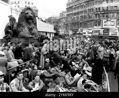 Krönungstag - Londoner Straßen voller Zuschauer. Mit einer ganzen Nacht und einem guten Teil des morgens vor ihnen ließen sich diese Leute auf dem Trafalgar Square nieder, um auf den größten Wettbewerb der Zeit zu warten - die Krönungsprozession. Ein weiterer Schauplatz ist einer von Landseers berühmten Löwen, auf dessen Rücken zwei Flieger hocken. 1. Juni 1953 Stockfoto