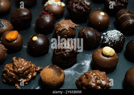 Verschiedene Geschmacksrichtungen von Schokoladenbonbons auf schwarzem Marmor Stockfoto