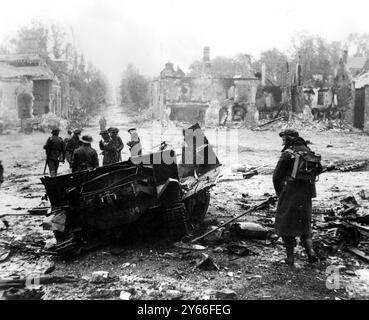 Die schreckliche Zerstörung des letzten Krieges ist auf diesem Bild von Tilly-sur-Seulles am 19. Juni 1944 zu sehen. Im Vordergrund steht ein Bren Carrier, der zerstört wurde, nachdem er eine Mine getroffen hatte. Die Stadt wurde am 19. Juni von britischen Truppen eingenommen und durch Schussfeuer schwer beschädigt, wobei viele zerstörte deutsche Panzer und Fahrzeuge auf den Straßen lagen, die stark abgebaut wurden. Königliche Ingenieure (einer rechts gesehen) waren schon bald an der Räumung der Minen - 2. Juni 1969 Stockfoto