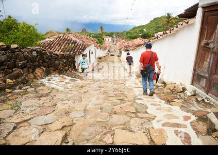 Guane, Santander, Kolumbien; 26. November 2022: Menschen gehen entlang einer ruhigen Kolonialstraße in dieser Touristenstadt. Stockfoto