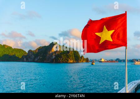 Die rote Flagge Vietnams weht auf einem Boot, das durch die Wahrzeichen der Ha Long Bay, ein beliebter Touristenort, segelt. Das Konzept des Tourismus in Vietnam und Südosten Stockfoto